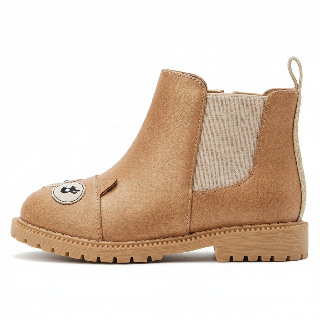Side profile view of girls tan distressed faux leather chelsea boot with owl face embroidery and gold glitter elastic panel on clean white background